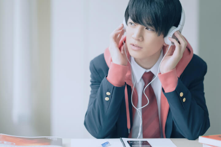 勉強の合間に音楽を聴いている男子学生
